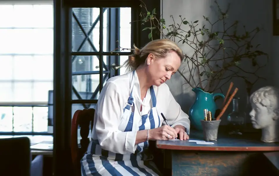 kvinne som sitter ved skrivebord og skriver