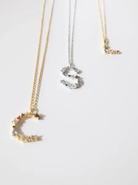 Tre smykker med bokstavanheng med små stendetaljer