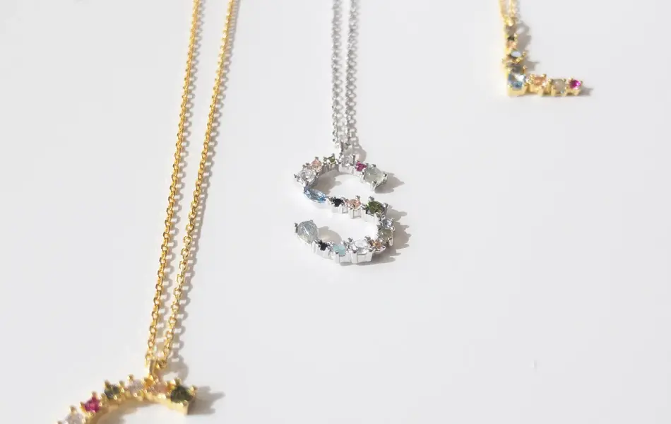 Tre smykker med bokstavanheng med små stendetaljer