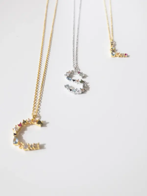 Tre smykker med bokstavanheng med små stendetaljer