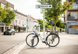 Bilde av en sykkel som lener seg mot et skilt ved en vei.