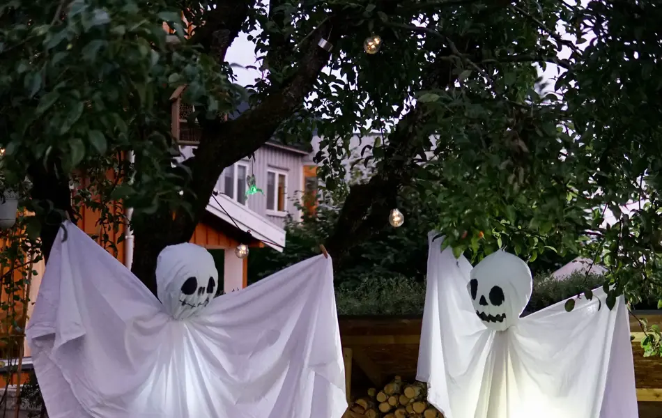 Hjemmelaget spøkelser av laken som henger fra trær
