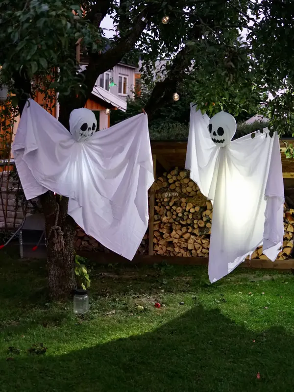 Hjemmelaget spøkelser av laken som henger fra trær