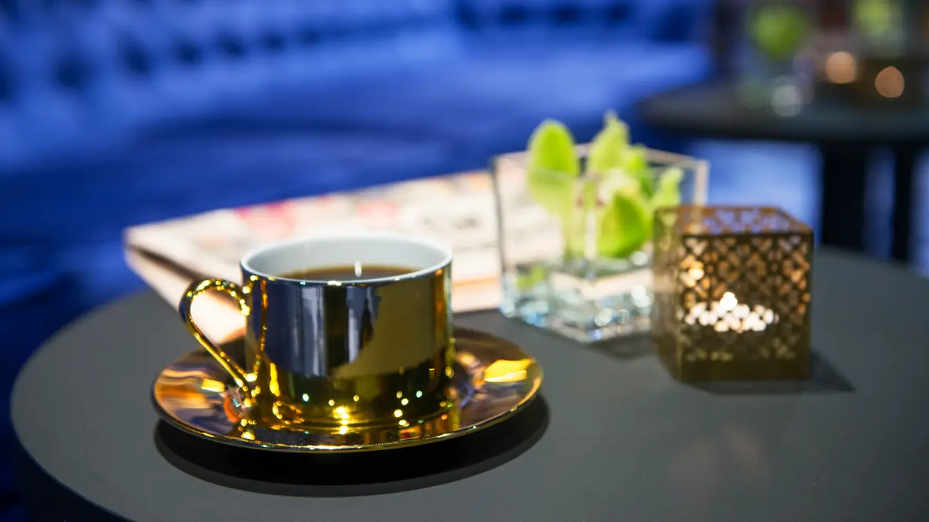 Blå brede sofaer og gullfarget kaffekopp og orkide på bord i lounge på Thon Hotel Terminus i Oslo sentrum nær Jernbanetorget