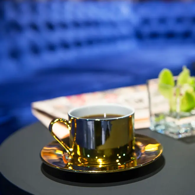 Blå brede sofaer og gullfarget kaffekopp og orkide på bord i lounge på Thon Hotel Terminus i Oslo sentrum nær Jernbanetorget