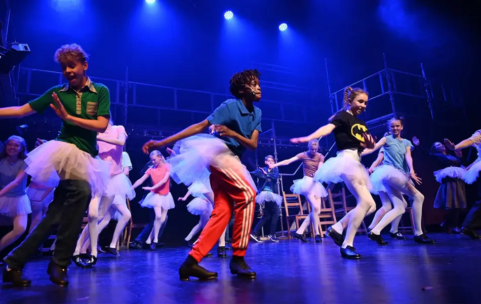 Barn og tenåringer som danser med på scene