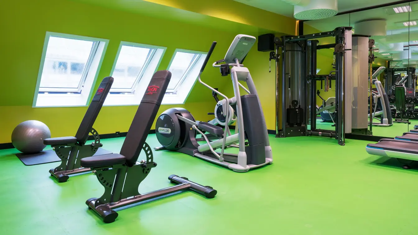 Lysegrønne gulv og gule vegger i treningsrom med forskjellige treningsapparater på Thon Hotel Terminus i Oslo sentrum