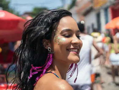 En kvinne med glitrende sminke på kinnene som går nedover gaten. Foto til artikkel om festivalsminke.