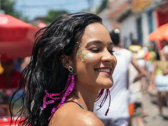 En kvinne med glitrende sminke på kinnene som går nedover gaten. Foto til artikkel om festivalsminke.