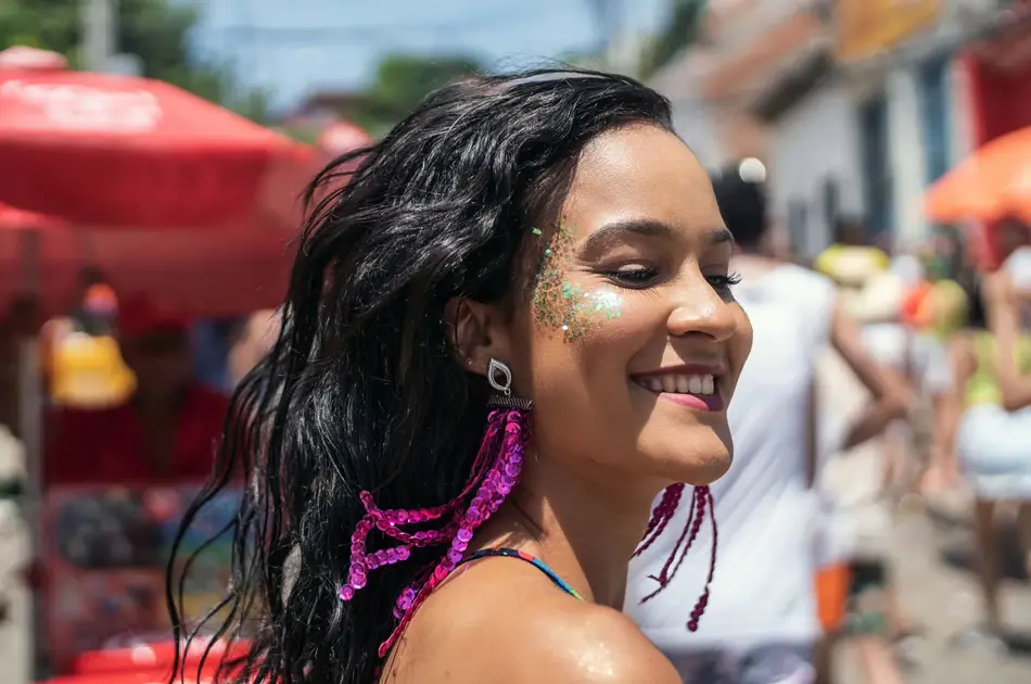 En kvinne med glitrende sminke på kinnene som går nedover gaten. Foto til artikkel om festivalsminke.