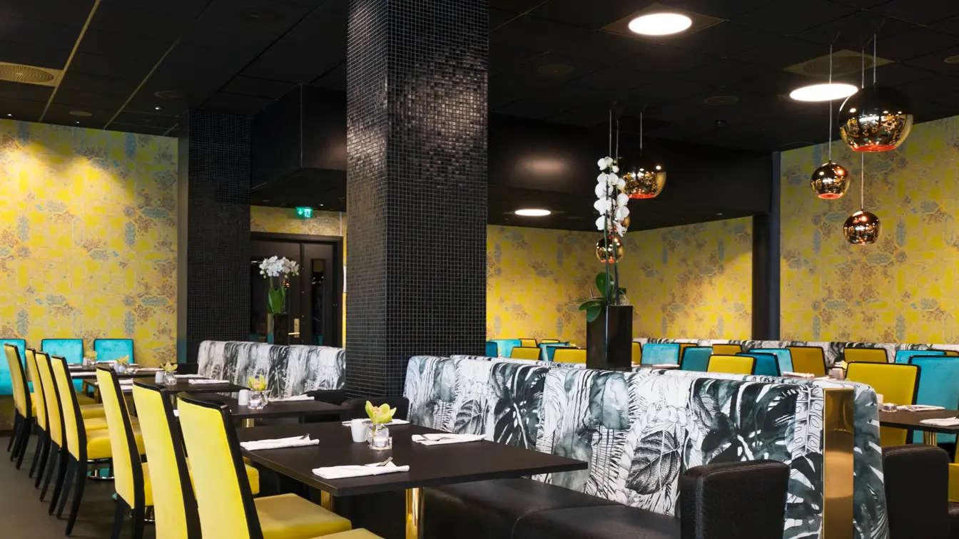 Frokostsal med gule og grønne stoler, gullkulede lamper i taket og gulmønstret tapet på veggene Hotel Stavanger midt i Stavanger sentrum