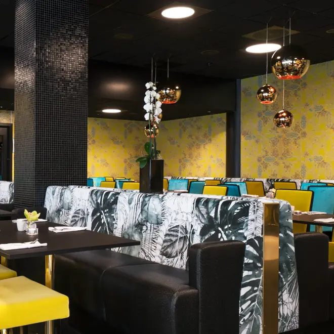 Frokostsal med gule og grønne stoler, gullkulede lamper i taket og gulmønstret tapet på veggene Hotel Stavanger midt i Stavanger sentrum