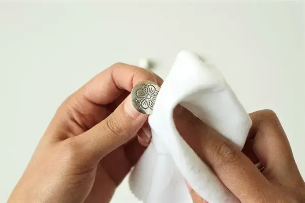 Bunadssølv/knapp som blir tørket med klut