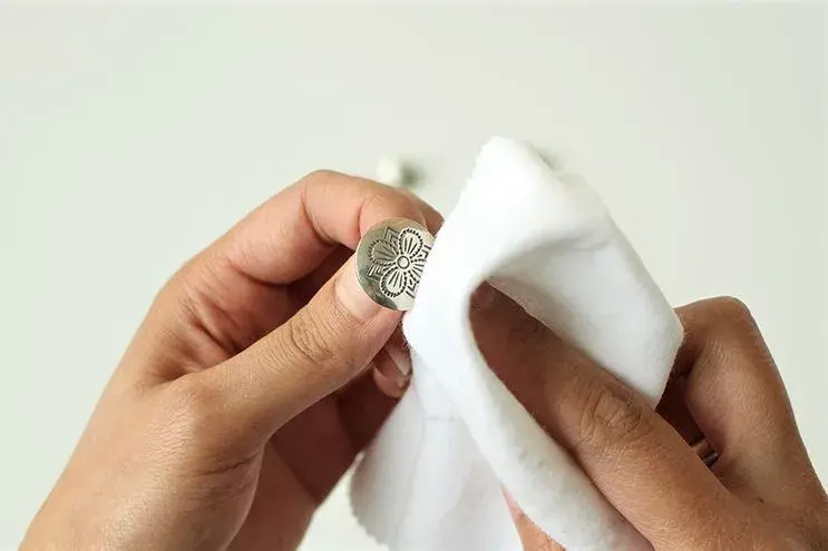 Bunadssølv/knapp som blir tørket med klut