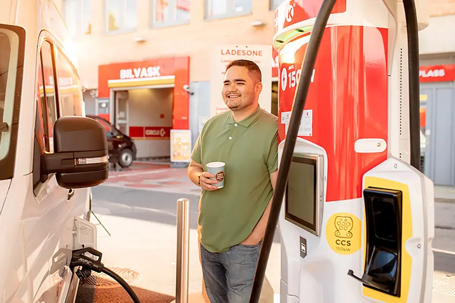 mann som fyller på drivstoff til en hvit varebil