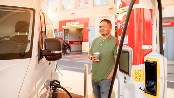 mann som fyller på drivstoff til en hvit varebil