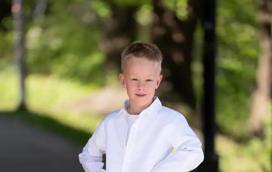 Liten gutt i hvit skjorte, grønn shorts, beige tøysko