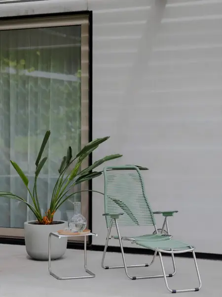 Grønn spagetti stol med en grønn plante