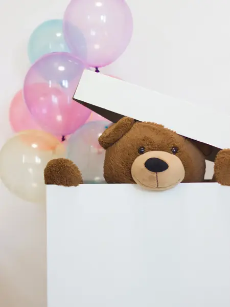 big teddy bear in a paper box with balloons on a white background. surprise for Valentine's Day. idea of celebration and gift.