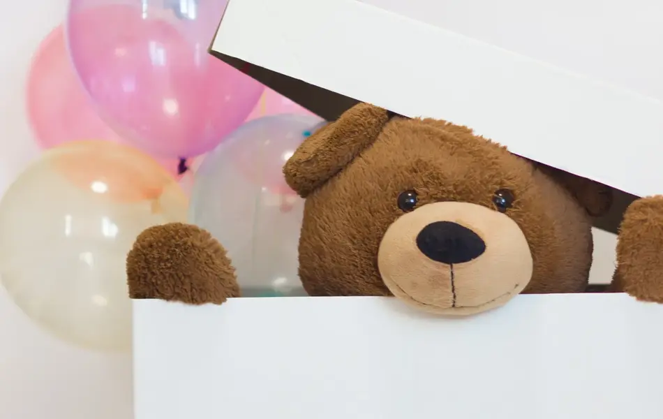 big teddy bear in a paper box with balloons on a white background. surprise for Valentine's Day. idea of celebration and gift.