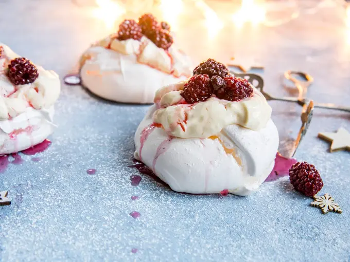 3 minipavlovaer med krem og bær på toppen