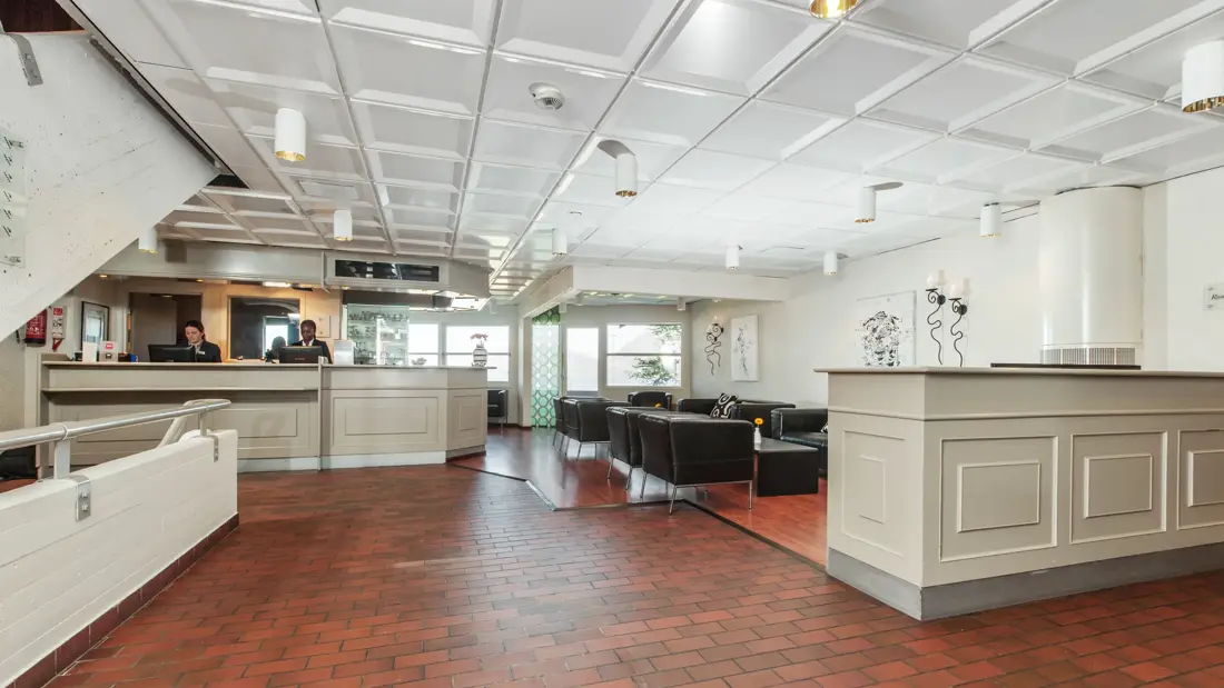 Lobby og resepsjonsområdet med mursteinsgulv og sorte sittemøbler hos Thon Hotel Sandnes