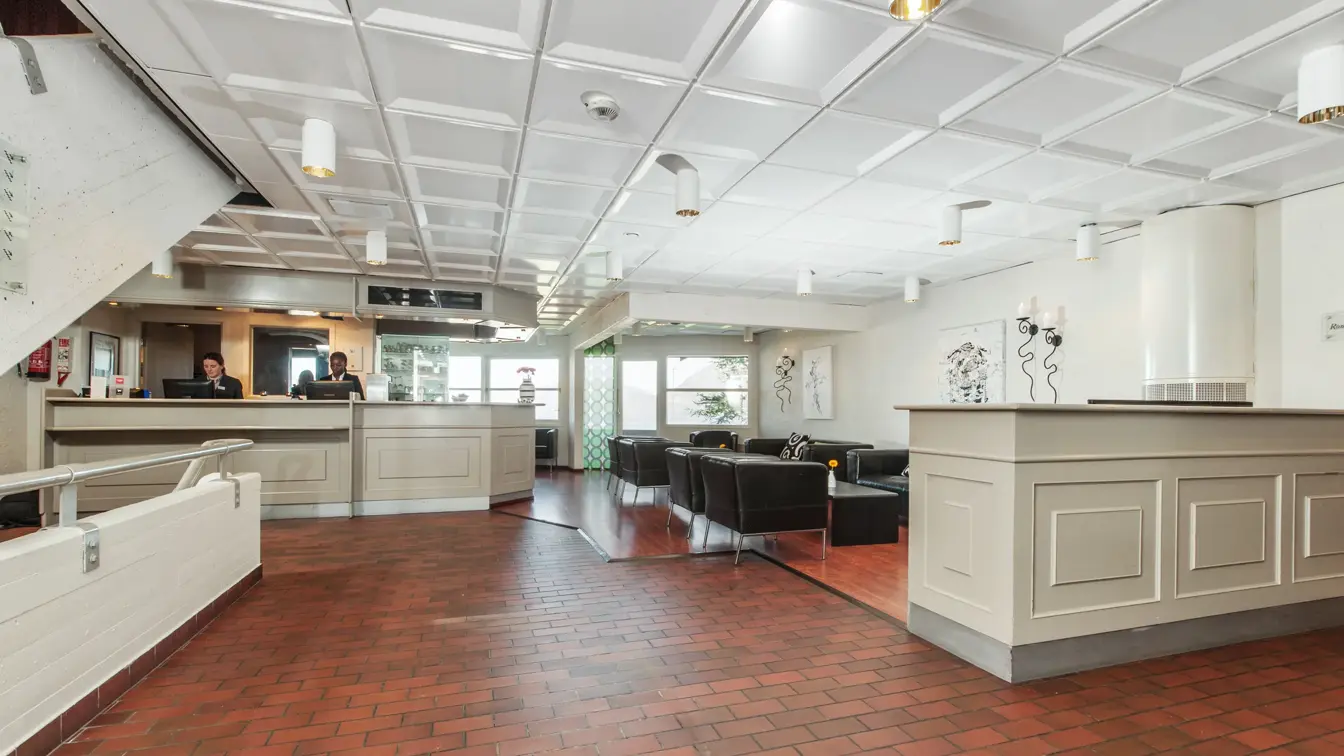 Lobby og resepsjonsområdet med mursteinsgulv og sorte sittemøbler hos Thon Hotel Sandnes