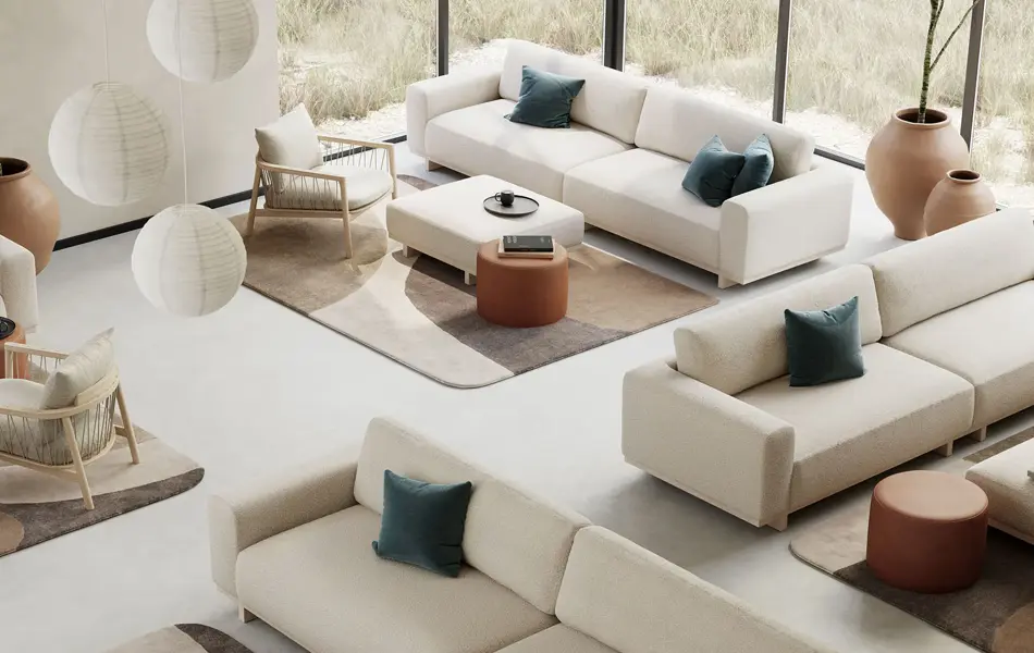 Rom med store vinduer dekorert med diverse hvite sofa, puffer, stuebord, tepper og lampe