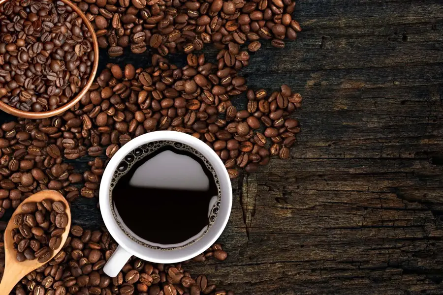Kaffekopp og bønner strødd på et bord