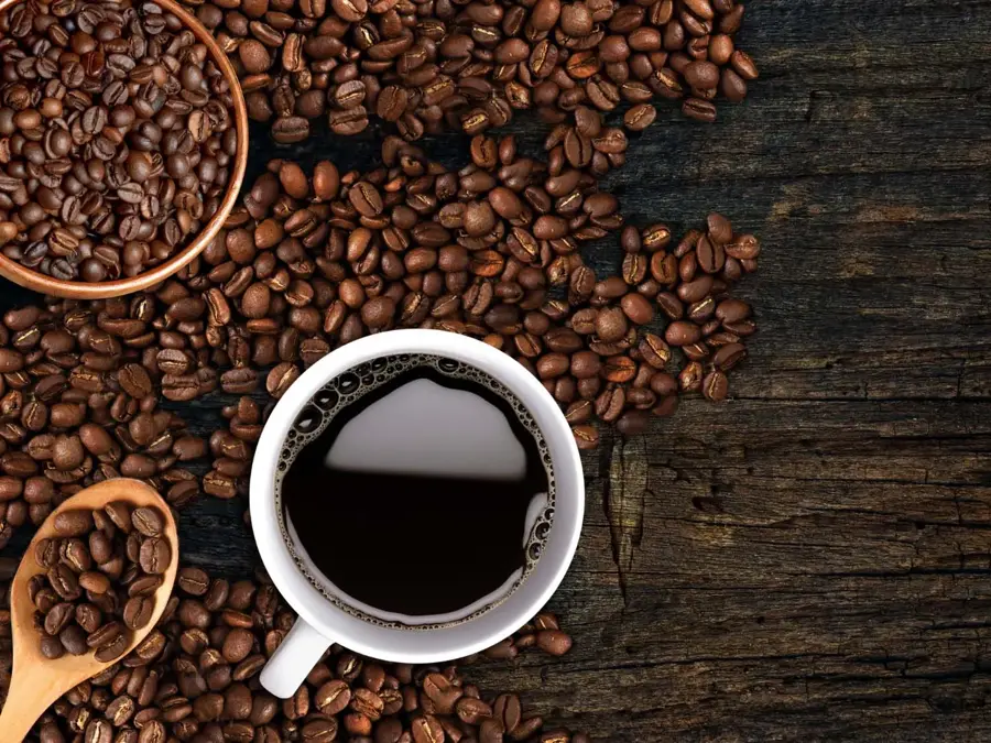 Kaffekopp og bønner strødd på et bord