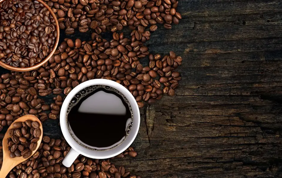 Kaffekopp og bønner strødd på et bord