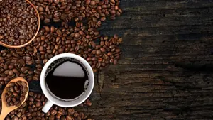 Kaffekopp og bønner strødd på et bord