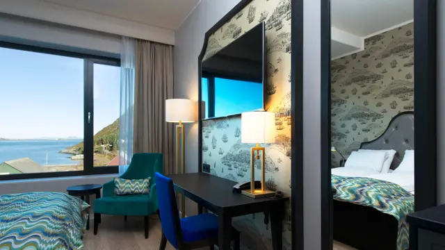 Dobbelseng, stol og arbeidspult på dobbeltrom på Thon Hotel Fosnavåg med utsikt utover havet
