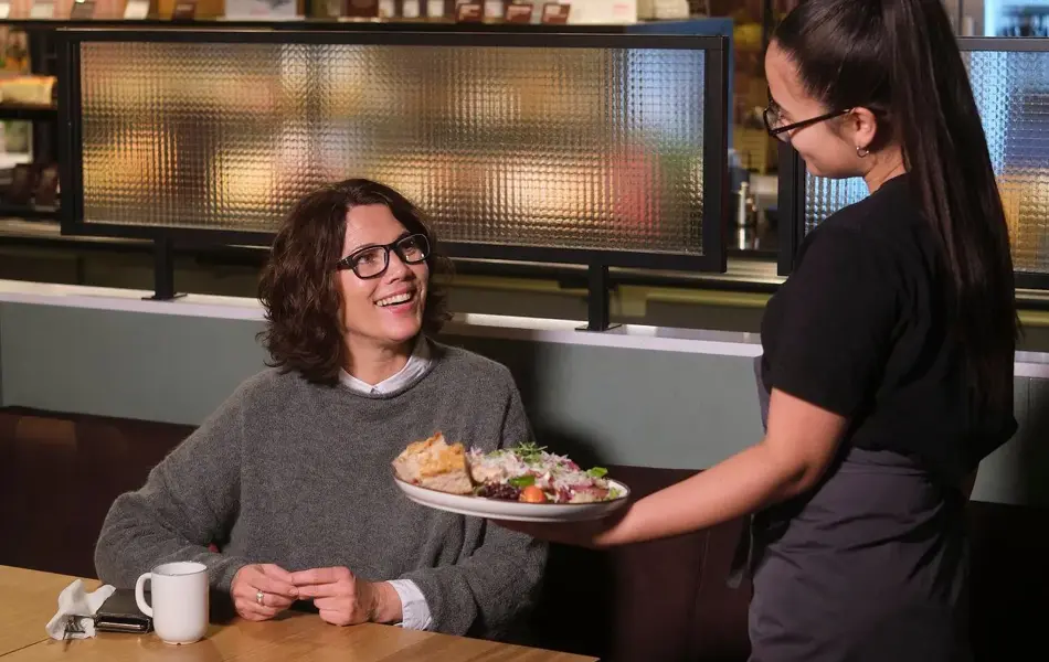 Kvinne på restaurant og en servitør som serverer mat