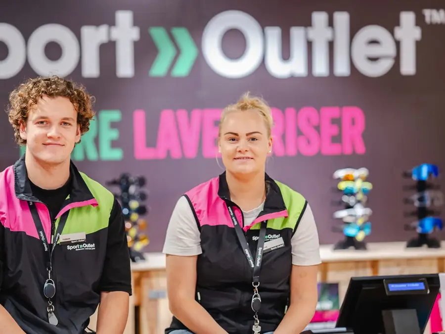 To som smiler til kamera med Sport Outlet logoen i bakgrunn