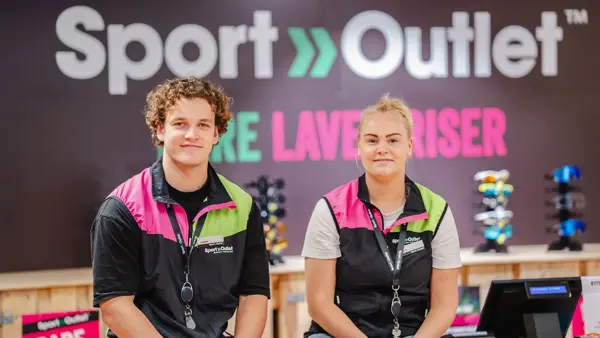To som smiler til kamera med Sport Outlet logoen i bakgrunn