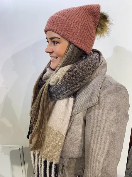 ansatt hos vero moda viser frem rød lue med dusk og fargerikt skjerf