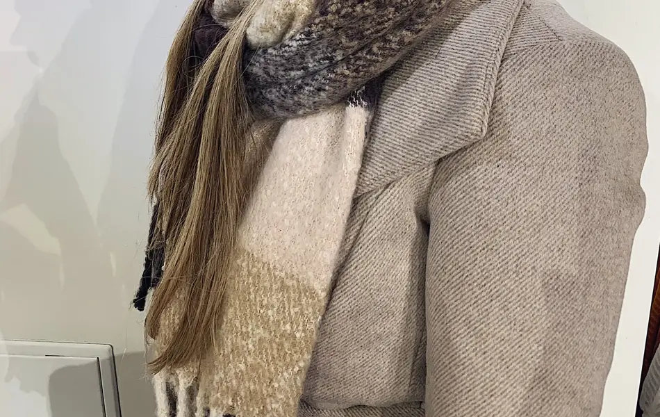 ansatt hos vero moda viser frem rød lue med dusk og fargerikt skjerf