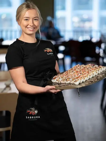 Dame som viser frem et fat med sushi