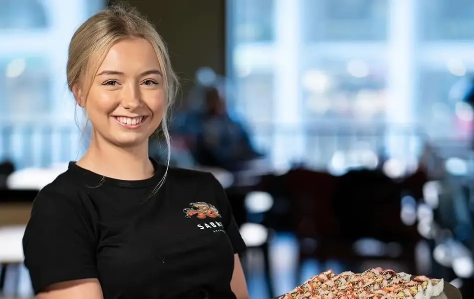 Dame som viser frem et fat med sushi