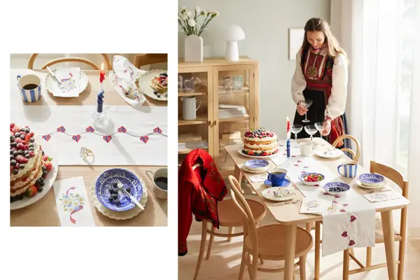 Bord dekket med hvit løper, servise i hvitt og blått, kaffekrus, stearinglys og kake. Jente i bunad står ved bordet.