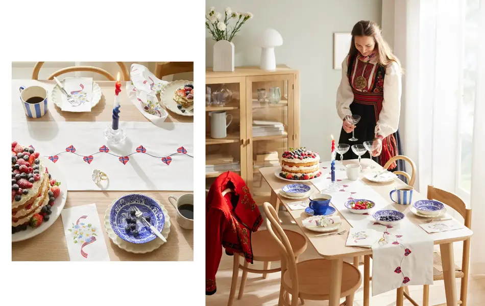 Bord dekket med hvit løper, servise i hvitt og blått, kaffekrus, stearinglys og kake. Jente i bunad står ved bordet.
