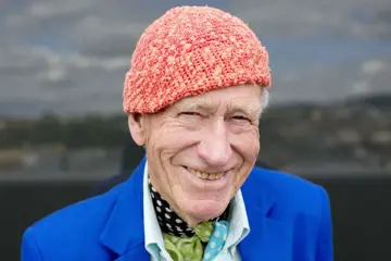 Et fotografi av Olav Thon, med sin signatur-lue på