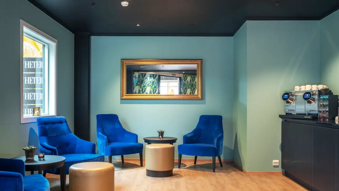 Turkise vegger, fire mørkeblå lenestoler, salongbord, puff, parkettgulv, vindu