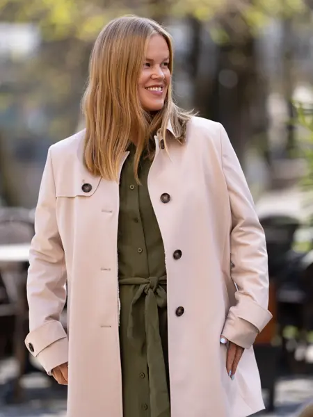 Dame med militærgrønn skjortekjole og beige frakk over.