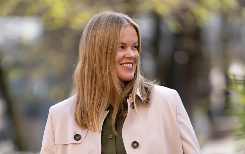 Dame med militærgrønn skjortekjole og beige frakk over.