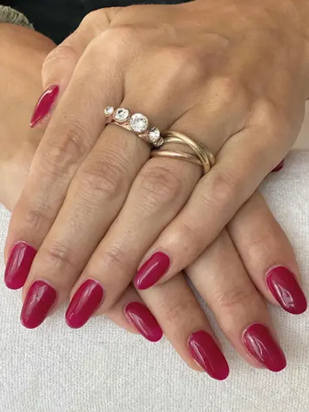 nærbilde av hender med nye negler, rød neglelakk