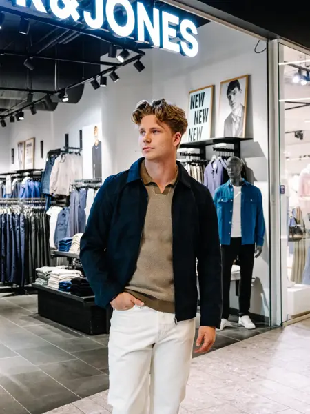 mann i vårklær står utenfor butikk