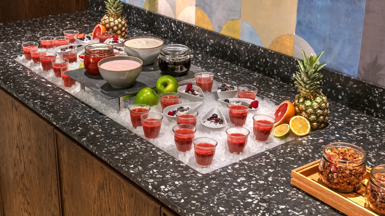 Pausebuffet med fargerike smoothies, frukt og yoghurt som står på is.