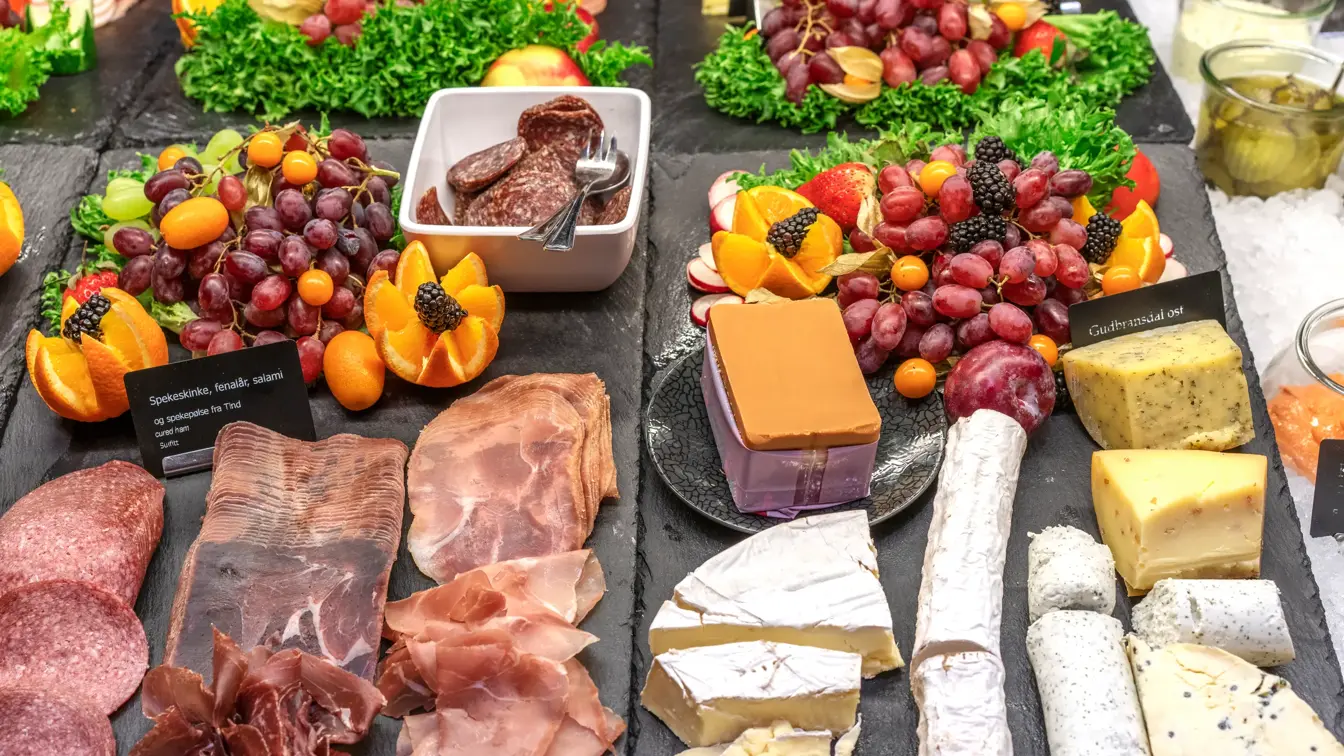 Frokostbuffén byr på spekemat, ulike oster, druer, appelsiner, bær og tilbehør som sur agurk m.m.